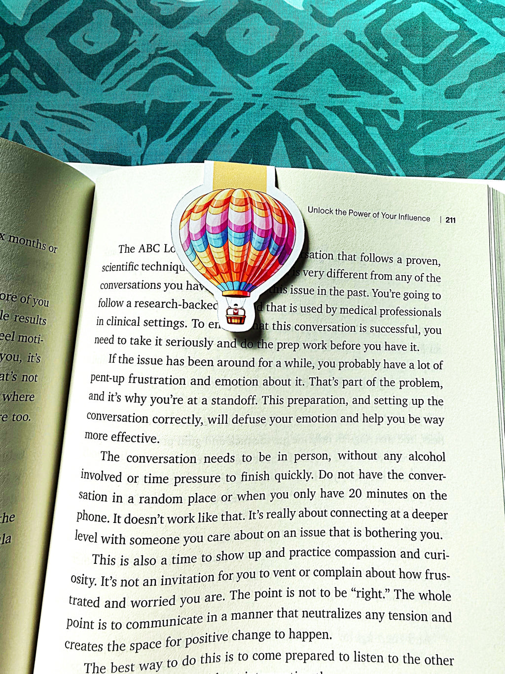 Colorful hot air balloon bookmark on an open book with a patterned green background