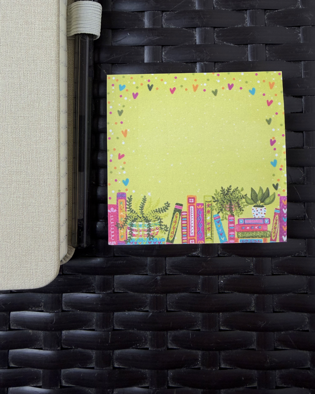 Colorful notepad with book and heart designs on a woven surface