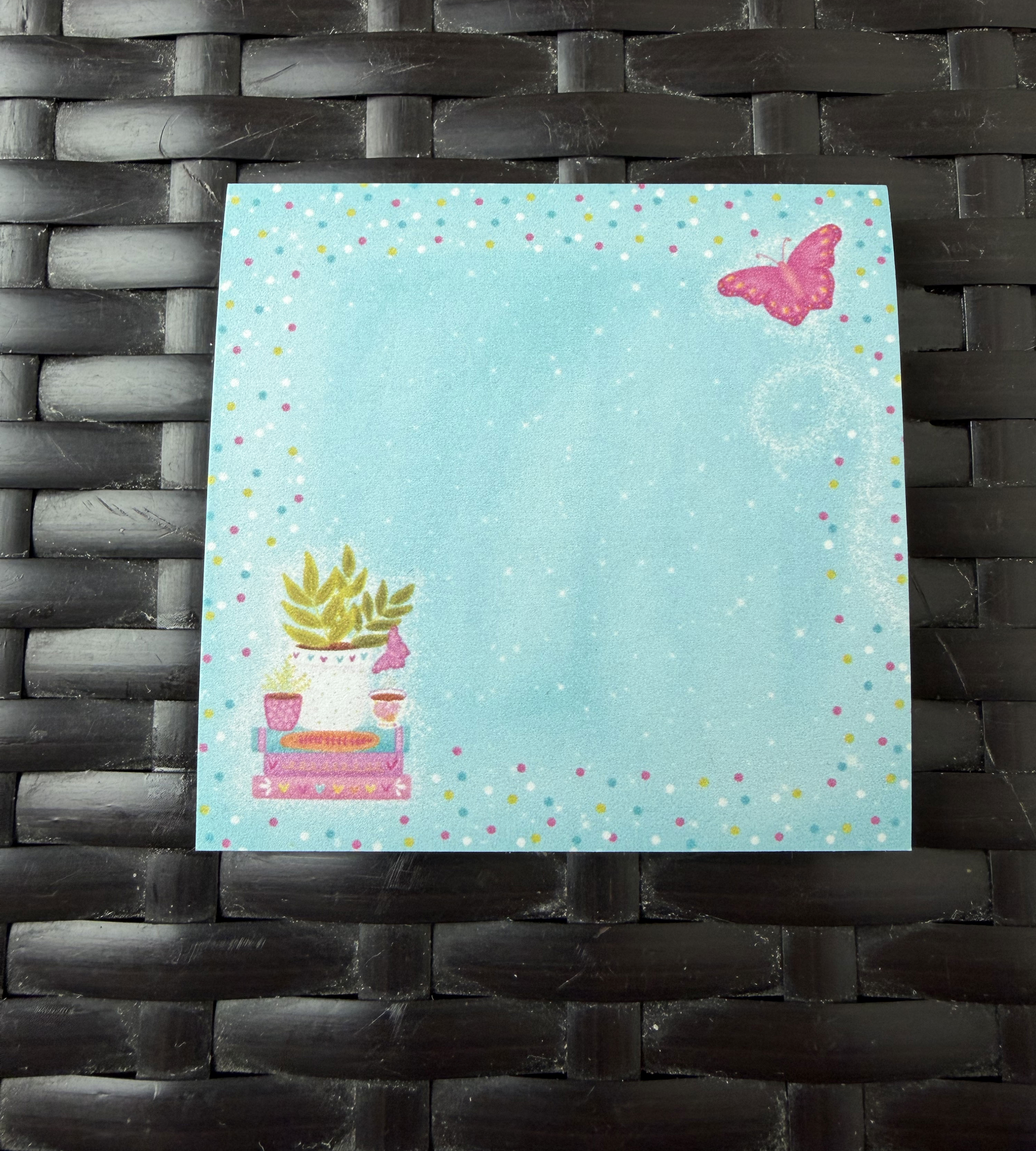 Sticky notes with a butterfly design on a textured black surface