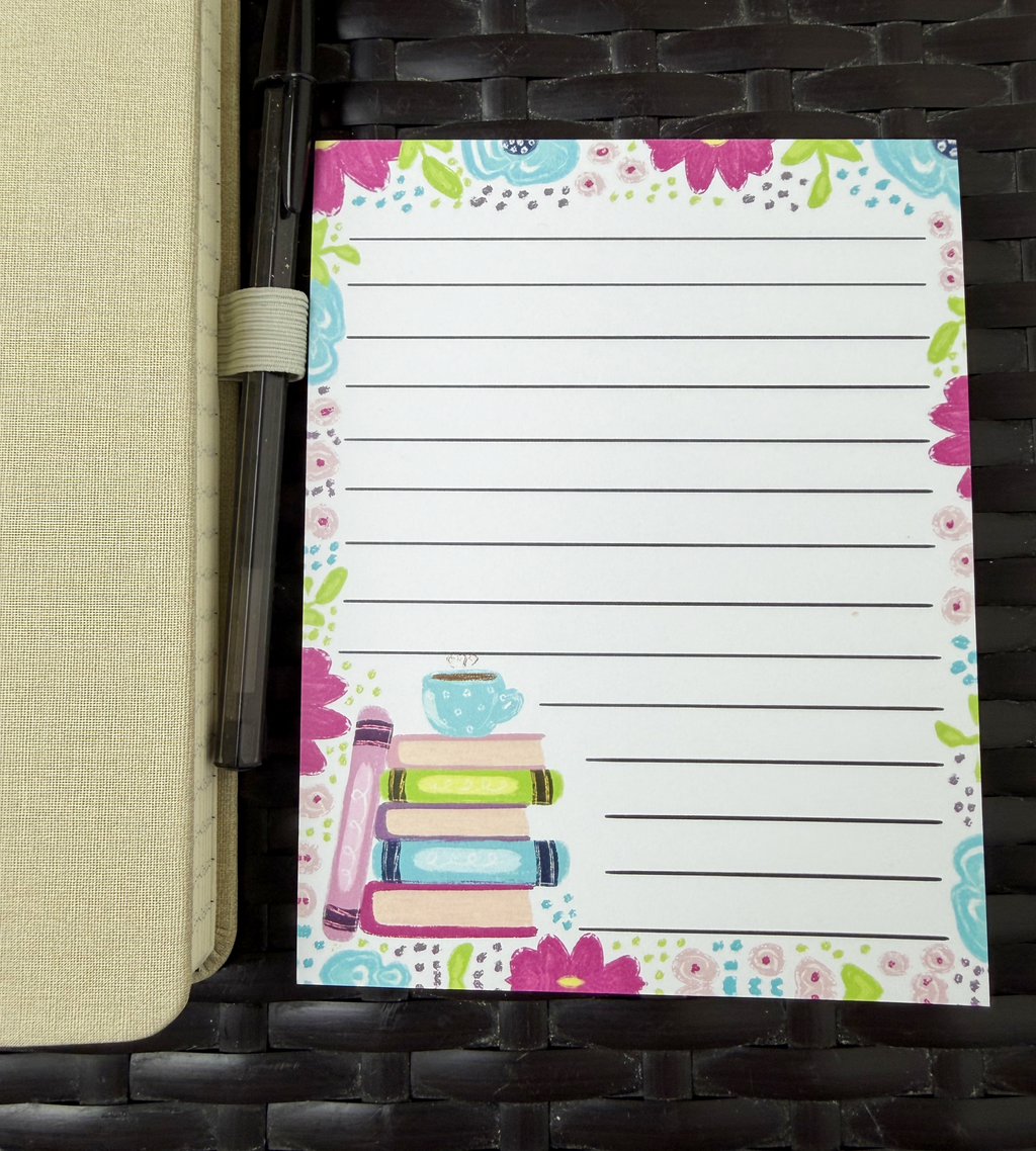 Floral-themed notepad with book illustration on a woven surface