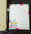 Floral-themed notepad with book illustration on a woven surface